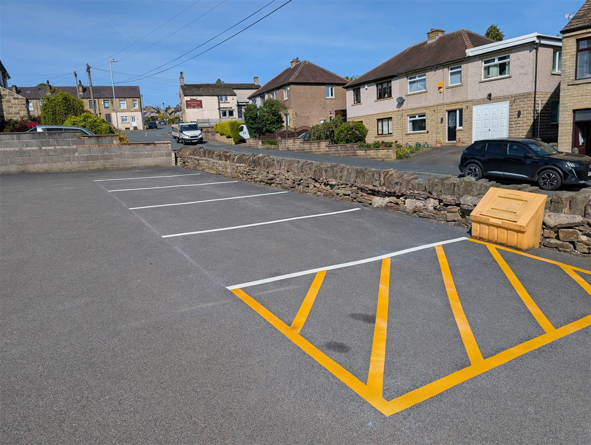 Car park marked with white thermoplastic bays and a yellow hatched keep-clear area